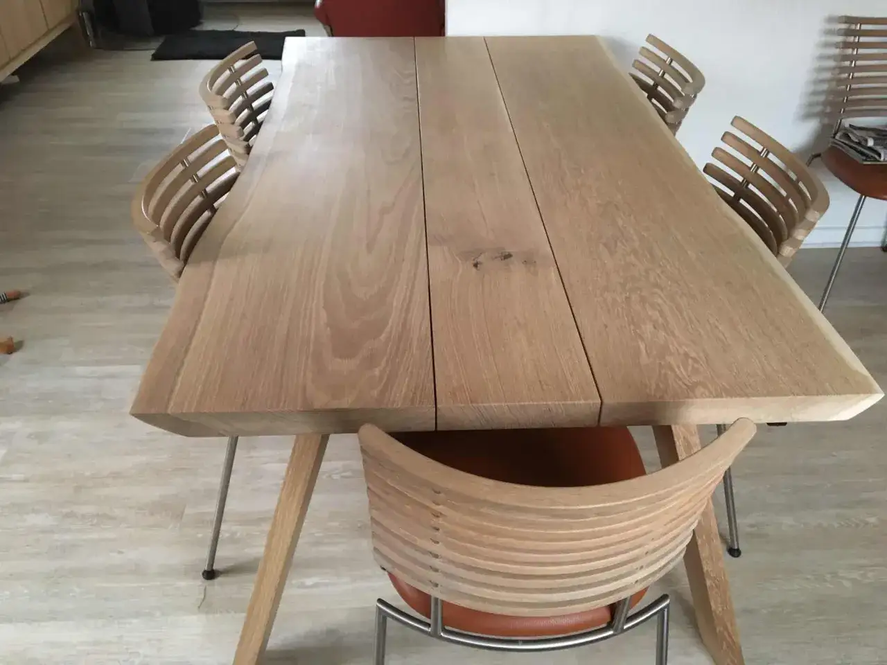 Ett modernt ekbord med en naturlig, pigmenterad oljeyta, omgivet av stilrena stolar med träribbor och lädersits.