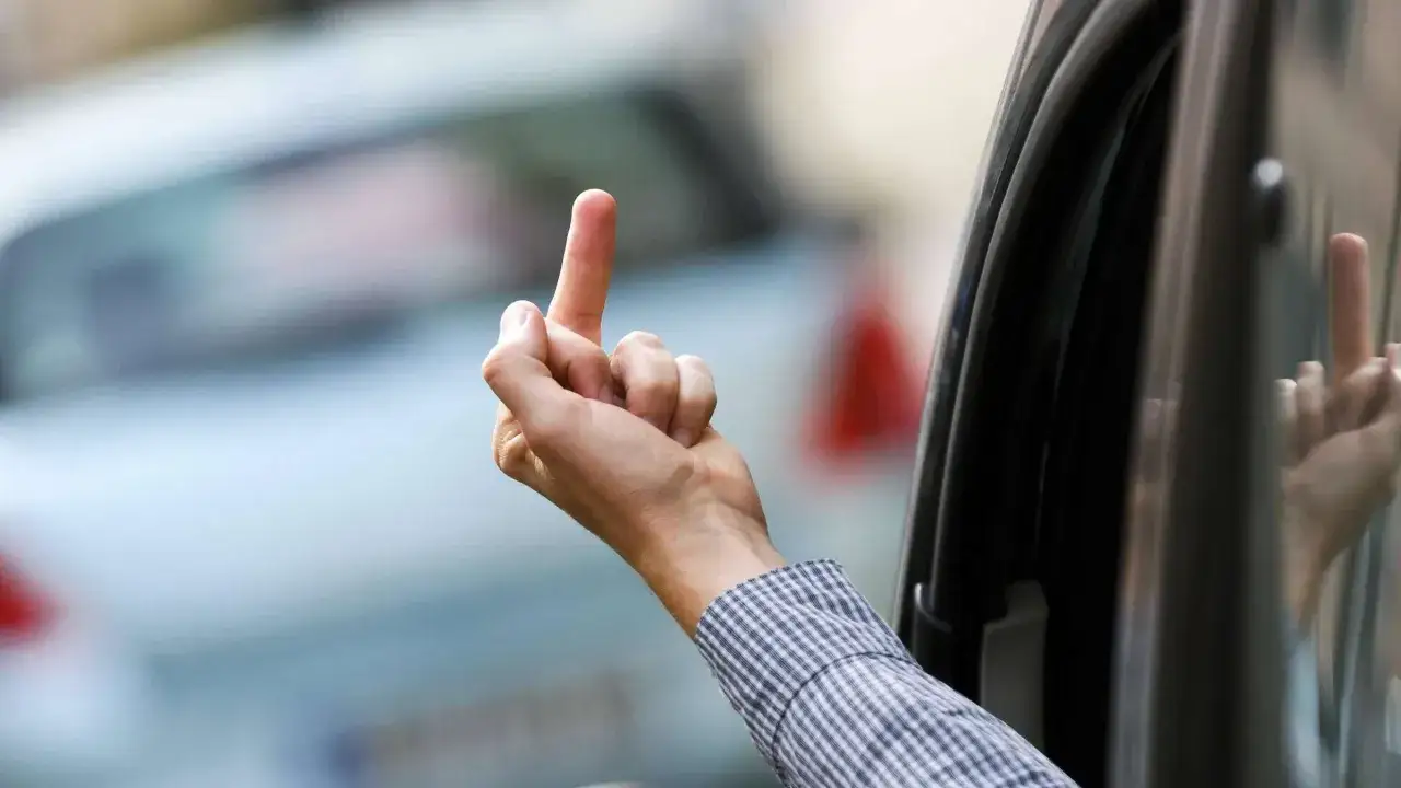 Hand im Auto zeigt den Mittelfinger. Eine Geste, die eine Strafe nach sich ziehen kann.