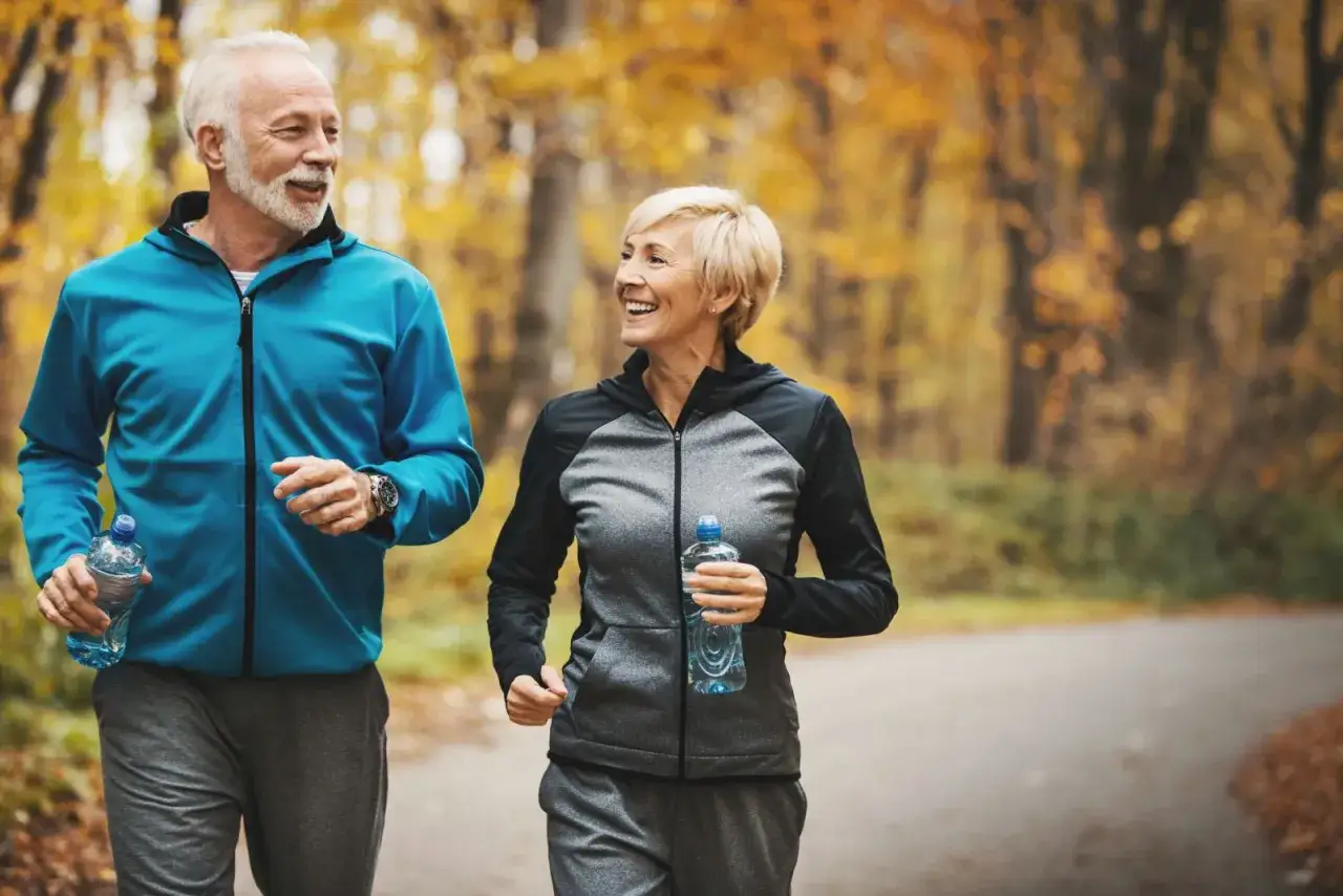 Ett glatt äldre par joggar i höstskogen, ett tydligt svar på frågan