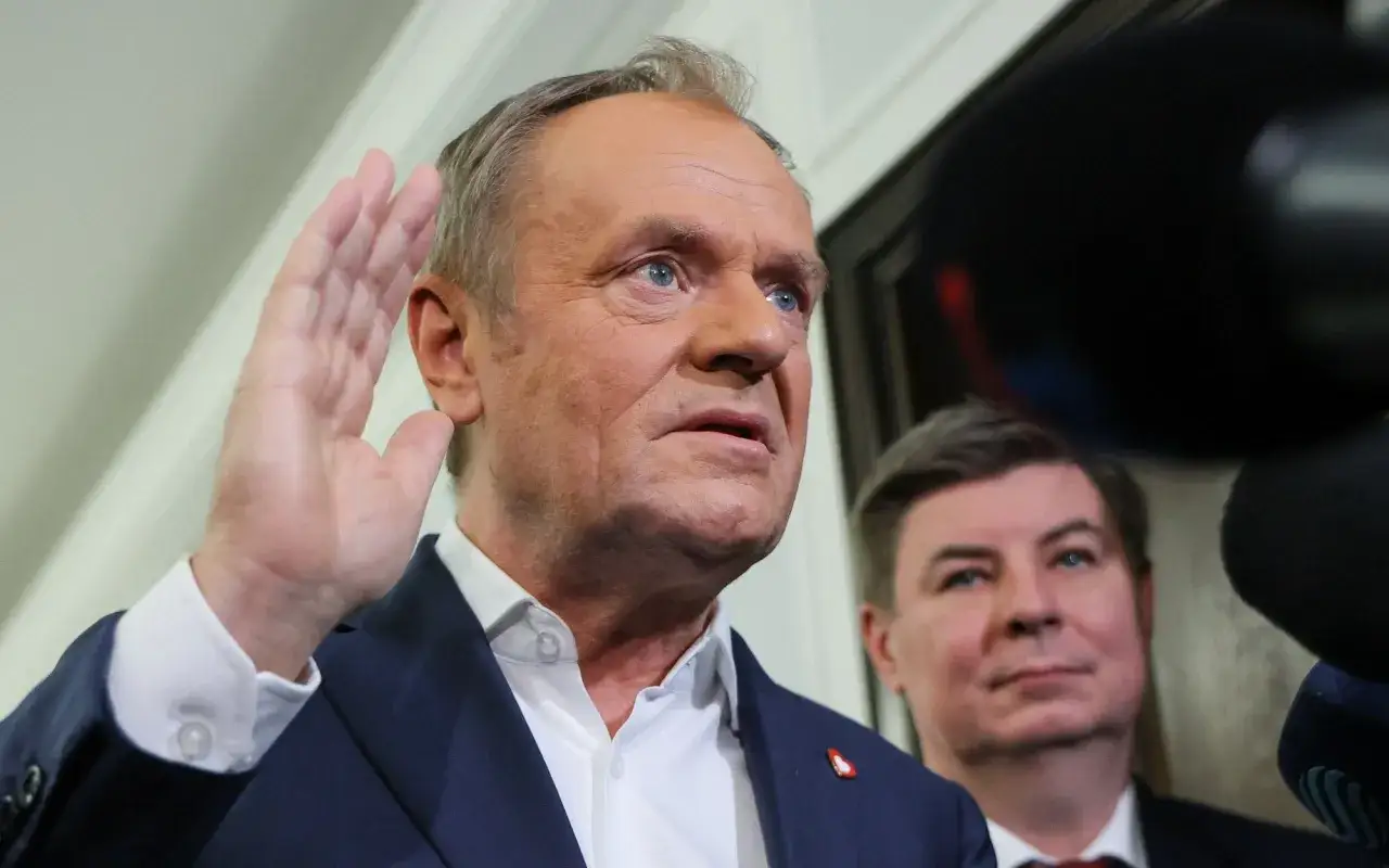 Donald Tusk, jakby ogłaszał koniec pewnej epoki, niczym upadek cesarstwa rzymskiego, podnosi rękę.