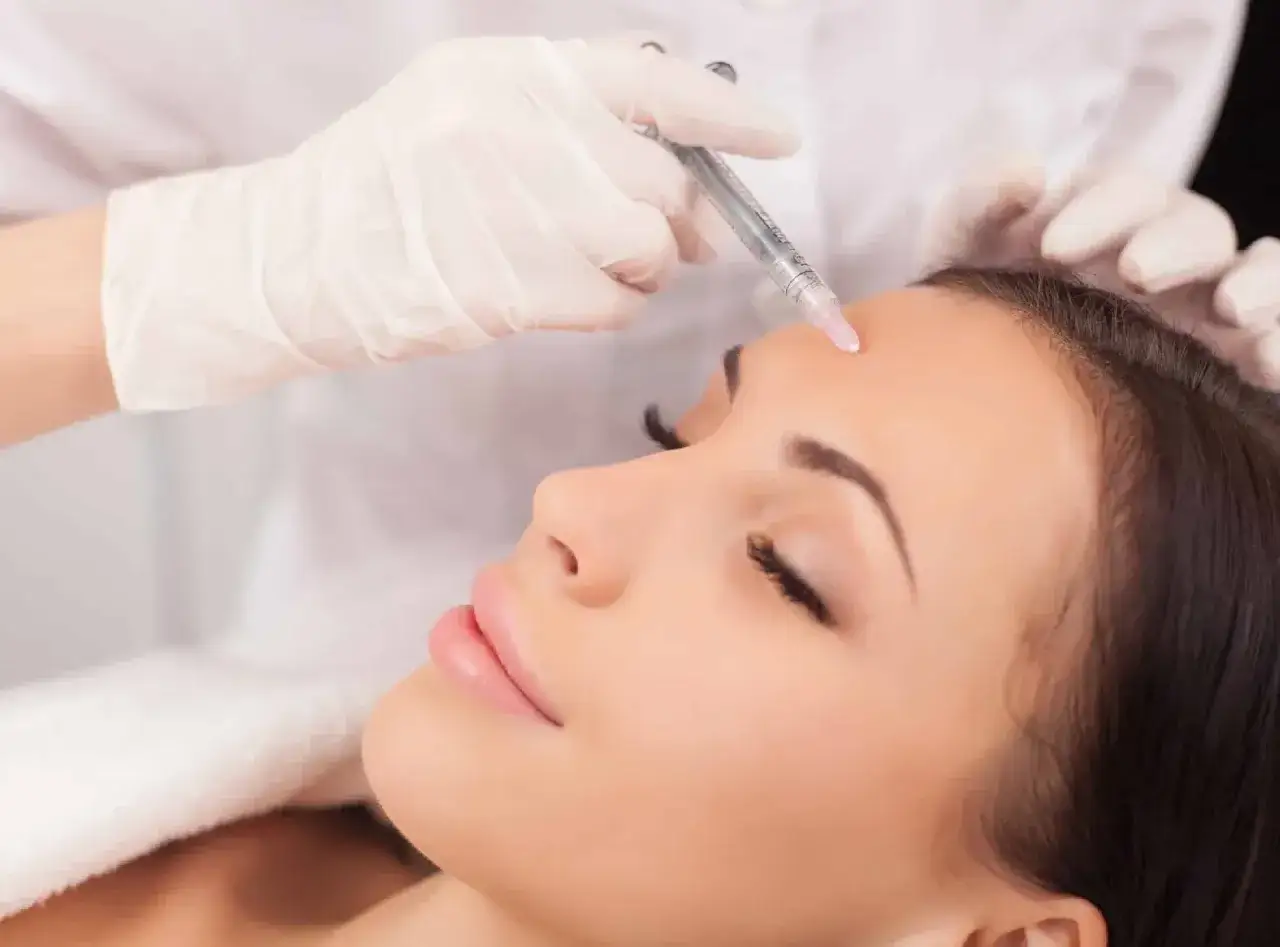 En kvinna får botox i pannan. Hon ser avslappnad ut, kanske drömmer hon om en kväll utan alkohol.