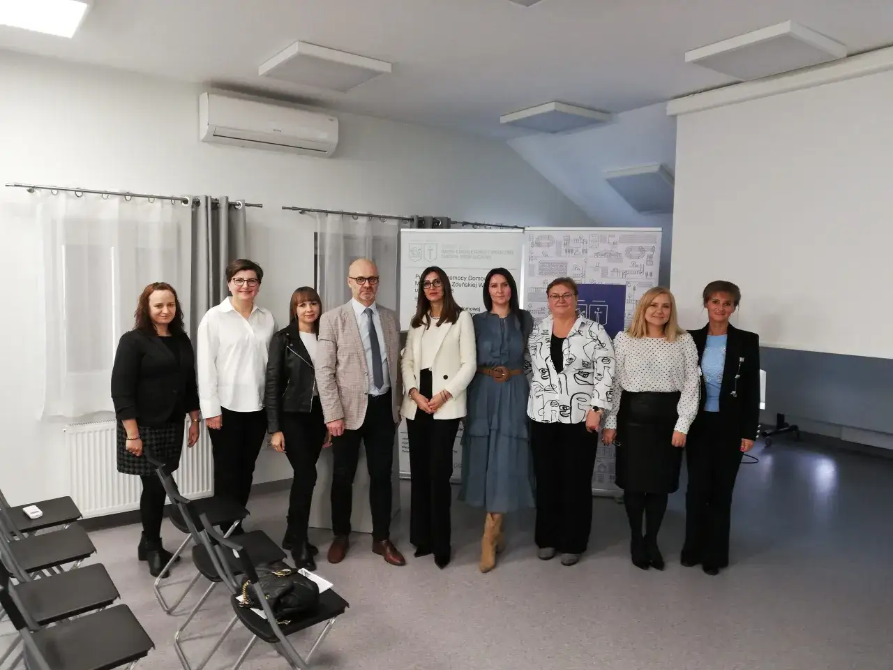 Grupa osób pozuje do zdjęcia. W tle baner Miejskiego Ośrodka Pomocy Społecznej w Zduńskiej Woli.