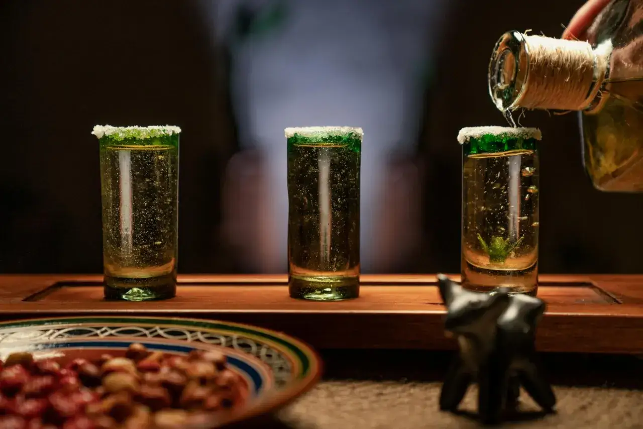 Trzy kieliszki tequili z solą na rancie, nalewanie z butelki. Czy sól na rancie szklanki faktycznie wzmacnia smak tequili?
