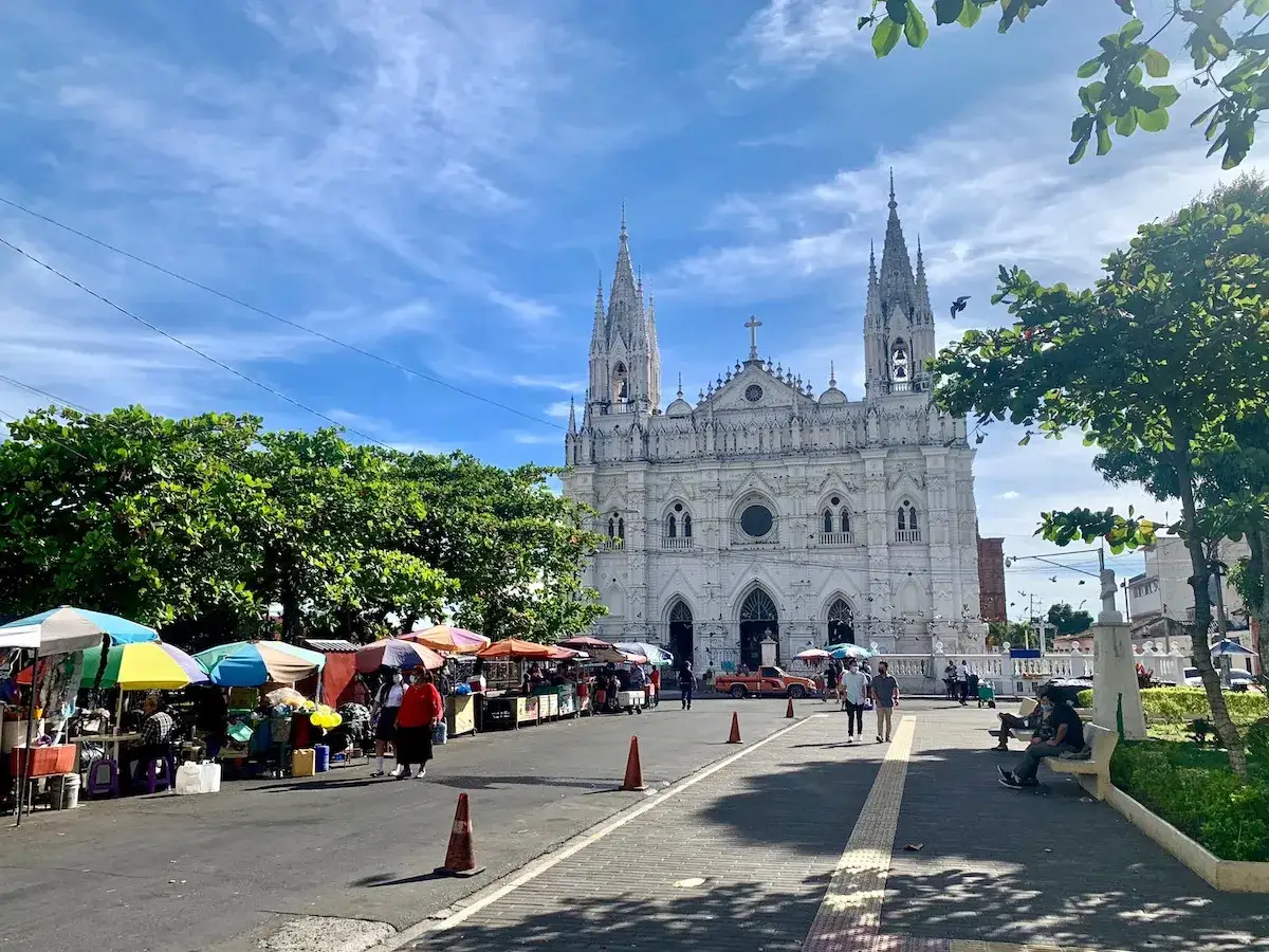Bunter Markt vor imposanter weißer Kirche in El Salvador. Ein perfekter Ort für **El Salvador Backpacking**-Abenteuer.