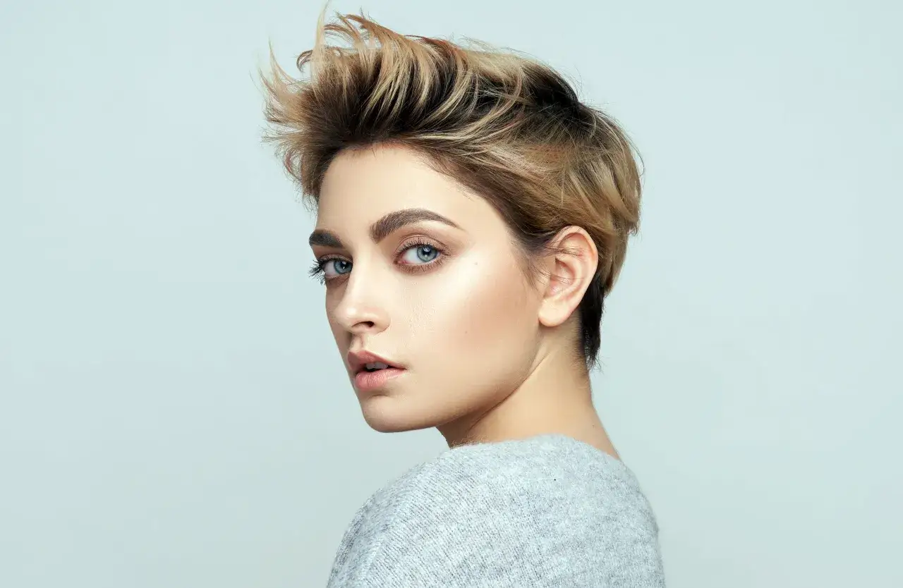 Kobieta z burzą blond włos&oacute;w, prezentująca modną fryzurę. Jej spojrzenie przyciąga uwagę.