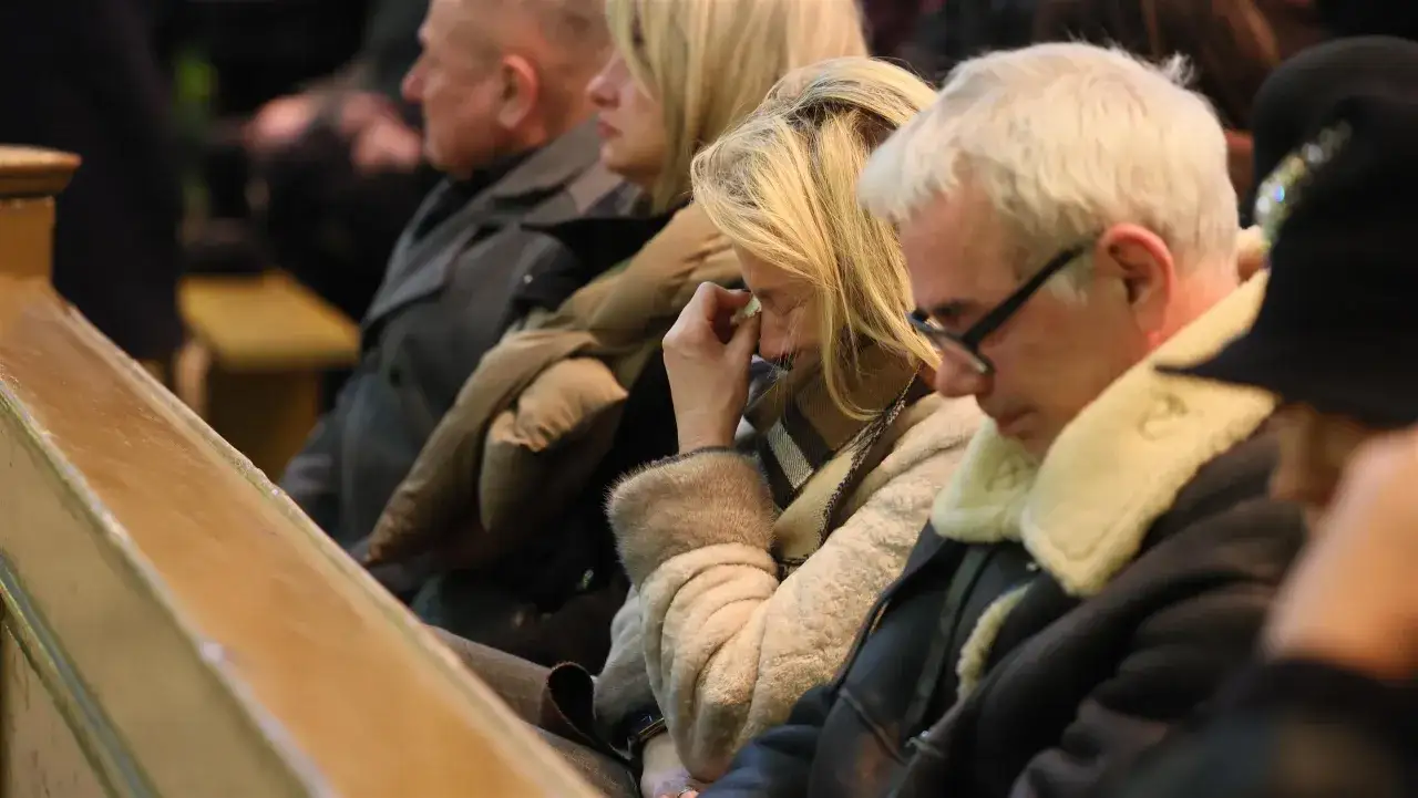 Smutek na pogrzebie Krzysztofa Respondka. Kobieta ociera łzy, siedząc obok mężczyzny w okularach.