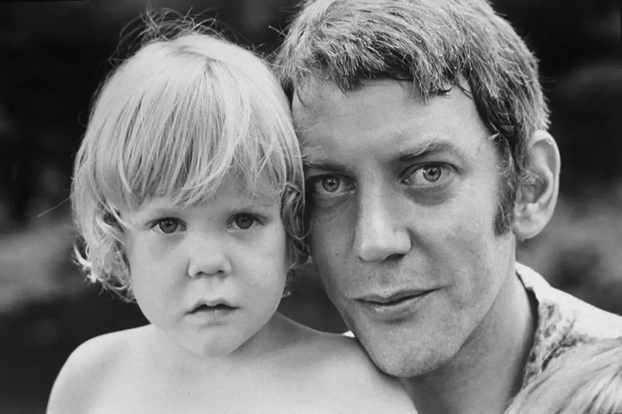 Donald Sutherland mit einem seiner Kinder. Ein intimer Moment zwischen Vater und Kind, eingefangen in Schwarz-Wei&szlig;.