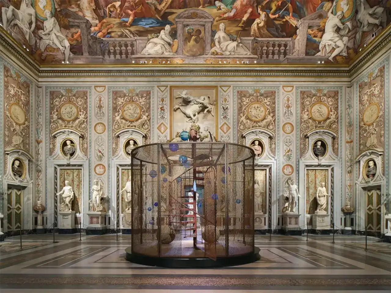 Intérieur orné de la Villa Borghese à Rome, avec une sculpture moderne en cage au centre et des fresques au plafond.
