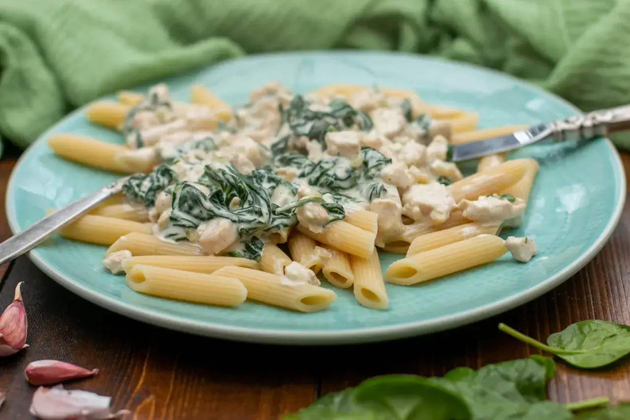 Penne z kurczakiem i szpinakiem w kremowym sosie z mascarpone. Pyszne danie na talerzu.