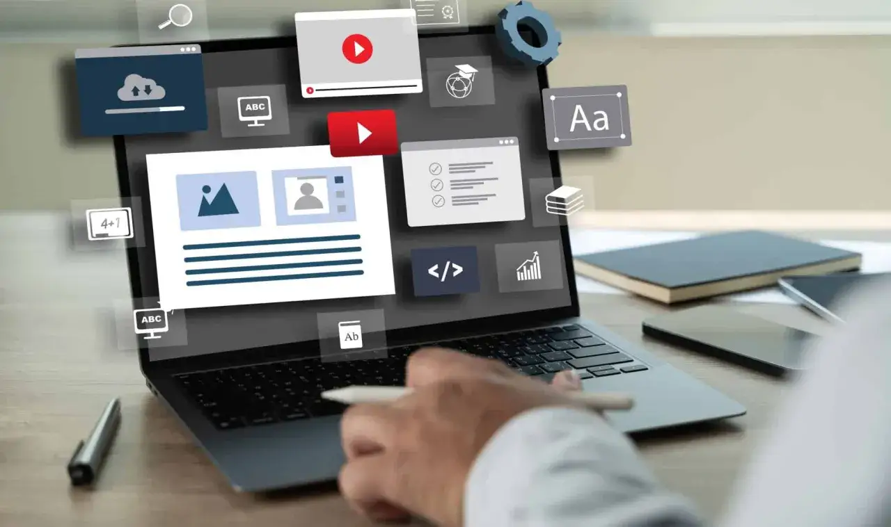 Ręka pisze na laptopie, na ekranie ikony symbolizujące tworzenie treści, wideo, kodowanie. To pokazuje, czym jest landing page.