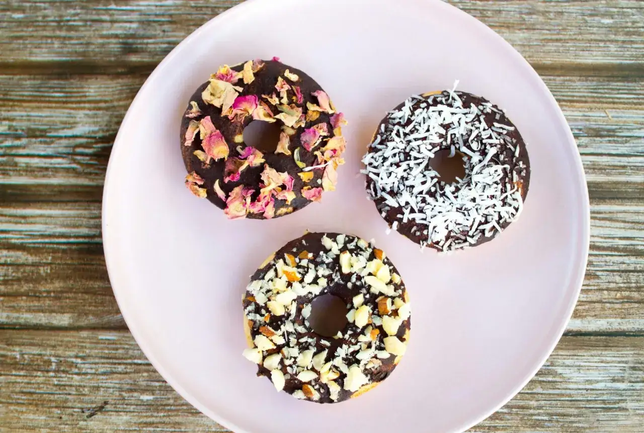 Tre chokladglaserade donuts med olika toppingar: torkade rosenblad, kokosflingor och hackade n&ouml;tter. Perfekt f&ouml;r att baka med barn!