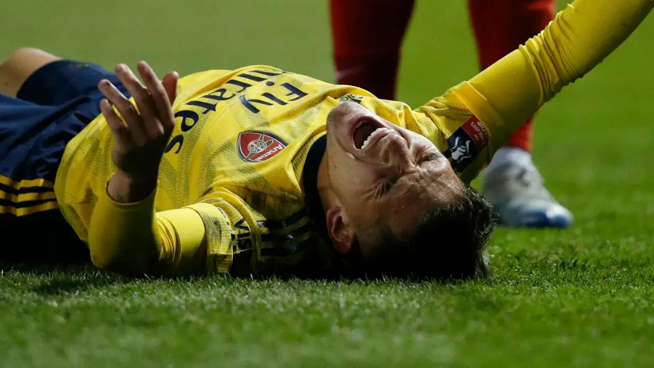 Jugador uruguayo del Arsenal, con la cara contra el c&eacute;sped, gritando de dolor.