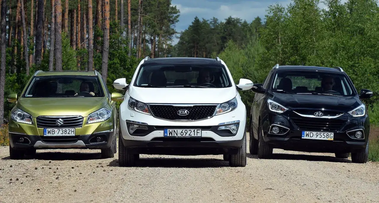 Trzy SUV-y z silnikiem wolnossącym: zielony Suzuki, białe Kia i czarne Hyundai, stoją na leśnej drodze.