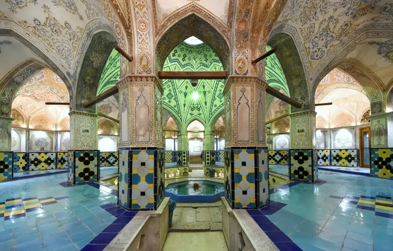 Ein prachtvoller Hamam in Marokko mit blau gekachelten Böden, kunstvollen Wandmalereien und einer zentralen Wasserquelle.