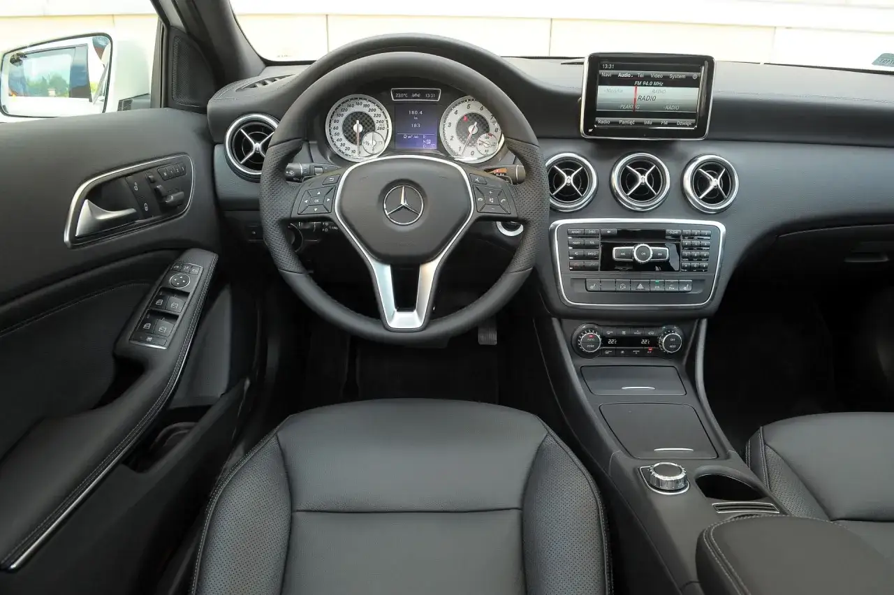 Wnętrze Mercedesa W176: kierownica, deska rozdzielcza z ekranem multimediów i panelem klimatyzacji.