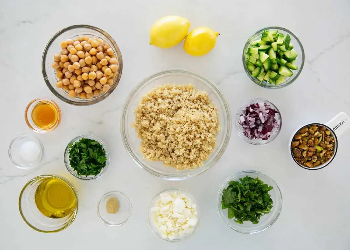 Ingredienser för jennifer aniston sallad recept: kikärtor, quinoa, gurka, rödlök, persilja, mynta, fetaost, pistagenötter, citroner, olivolja, honung, senap och salt.