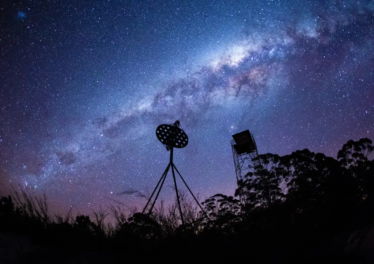 Un antico **obiettivo per fotografare le stelle** domina la scena sotto la Via Lattea.