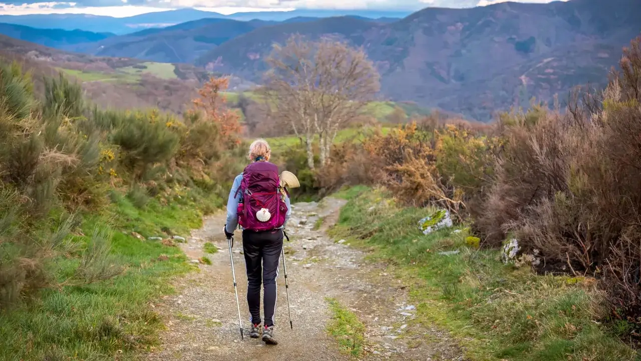 Peregrina avanza por un sendero rural, disfrutando del camino de Santiago en 6 etapas.