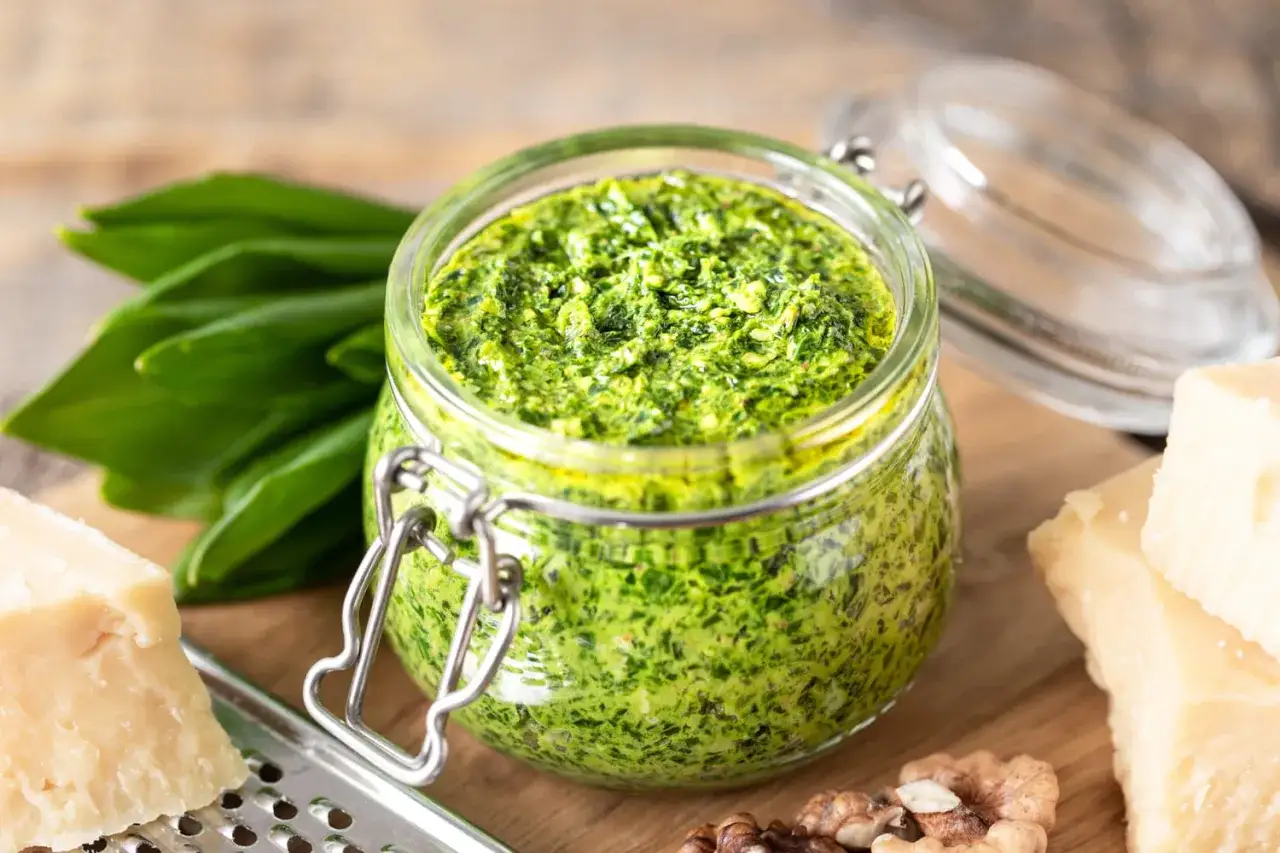 Pesto vert vif dans un bocal, pr&eacute;par&eacute; avec de l'ail des ours frais, du parmesan et des noix.