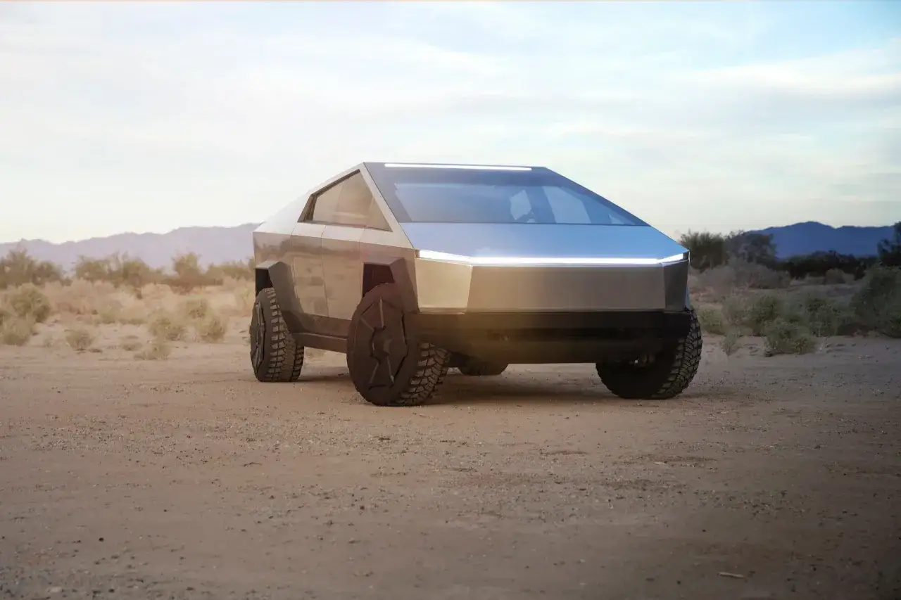Futurystyczny Cybertruck Tesla na pustynnym tle. Jego kanciasta sylwetka i ostre linie przyciągają wzrok.