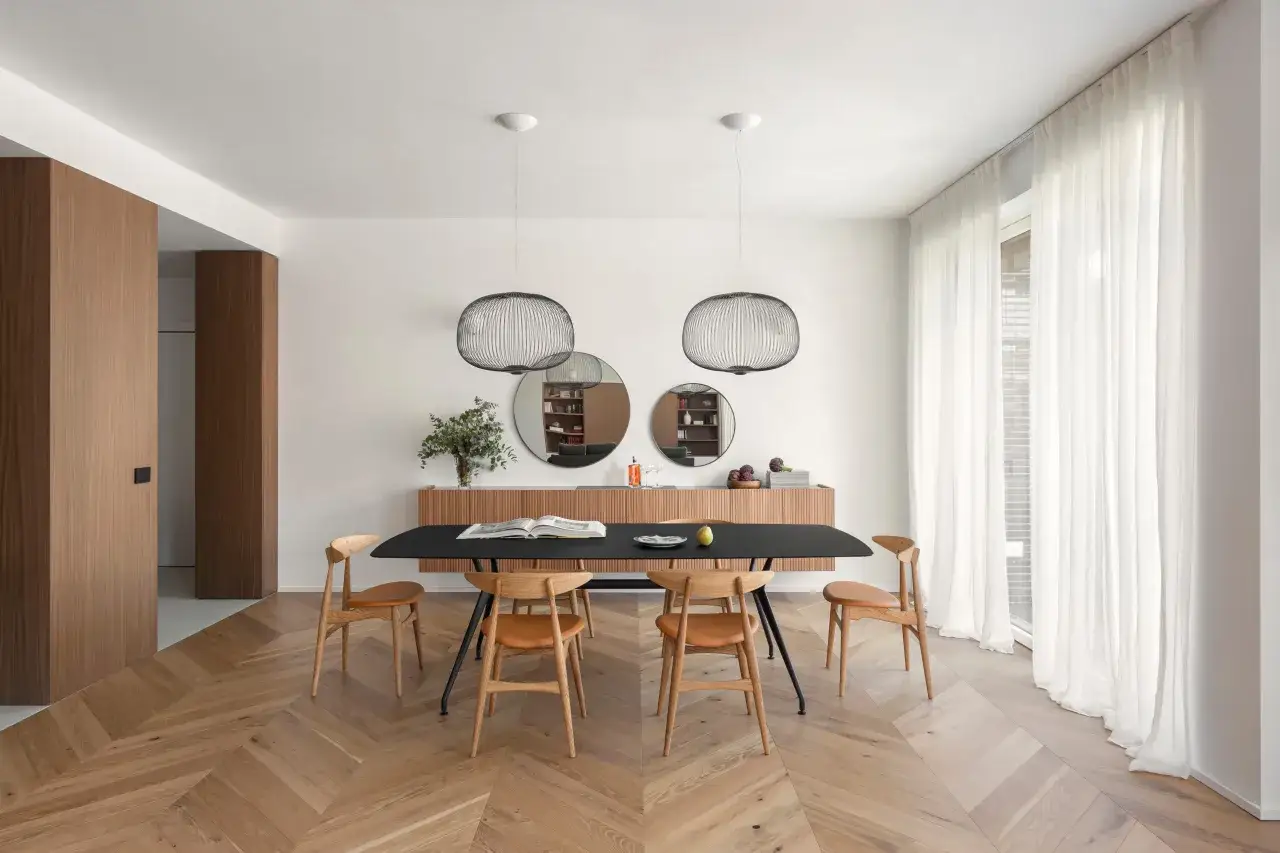 Un'elegante sala da pranzo con un tavolo nero, sedie in legno e un mobile a parete. L'ambiente &egrave; perfetto per arredare sala da pranzo con stile moderno.