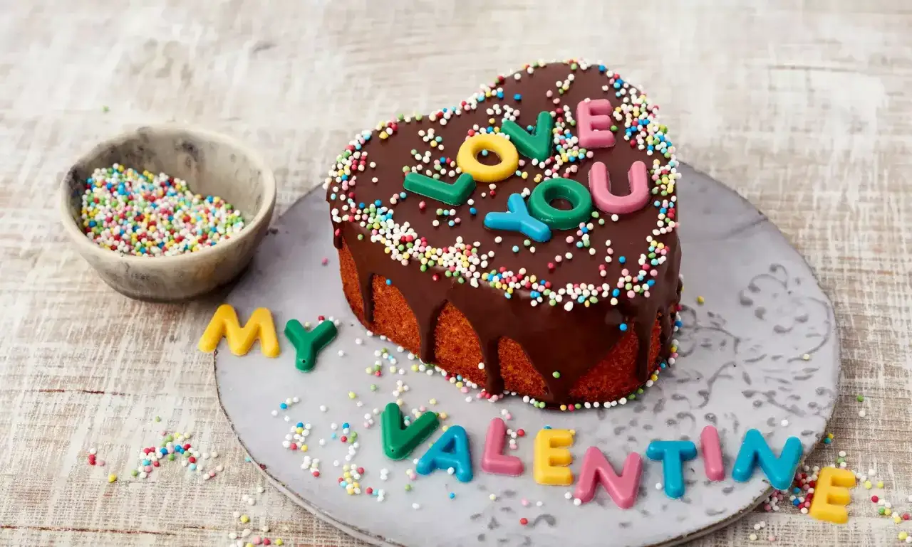 Herzf&ouml;rmiger Schokoladenkuchen mit bunten Streuseln und Buchstaben, die 