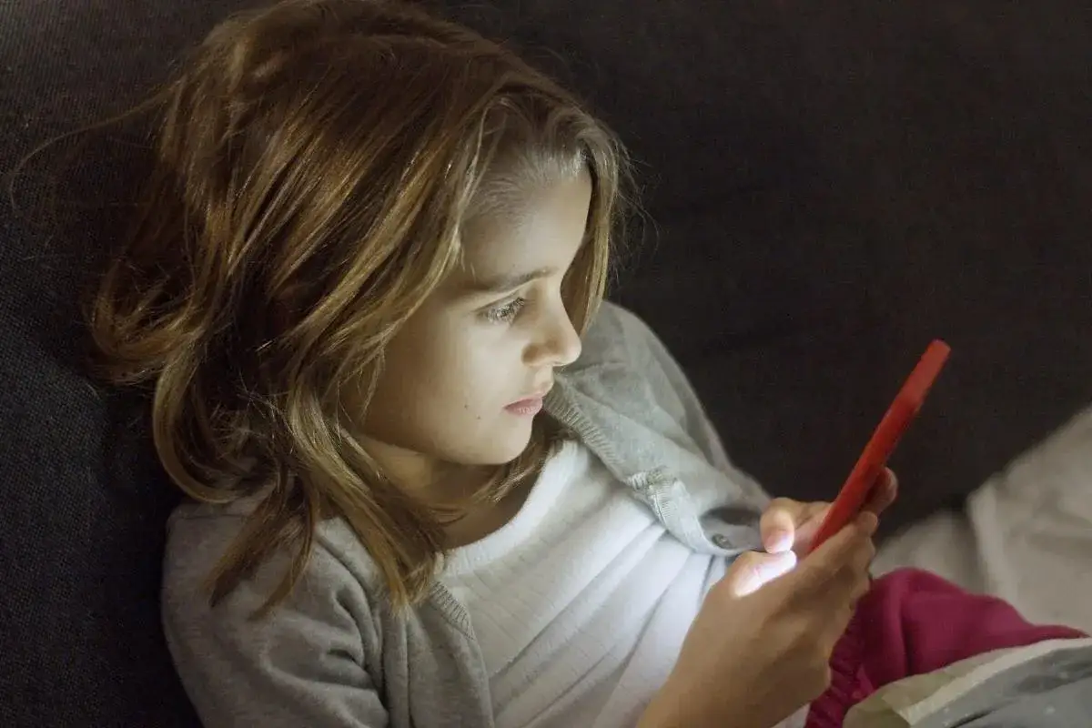 Dziewczynka z telefonem w ręku. Czy rodzic ma prawo sprawdzać dziecku telefon? Dylemat współczesnych rodziców.