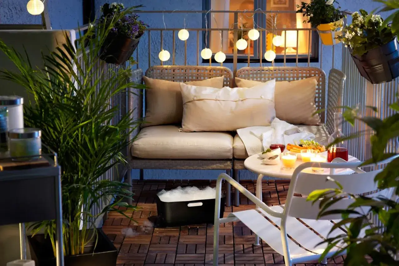 Wąski balkon w bloku inspiracje: przytulna kanapa, stolik z przekąskami i świecami, wiszące lampiony tworzą magiczny nastrój.