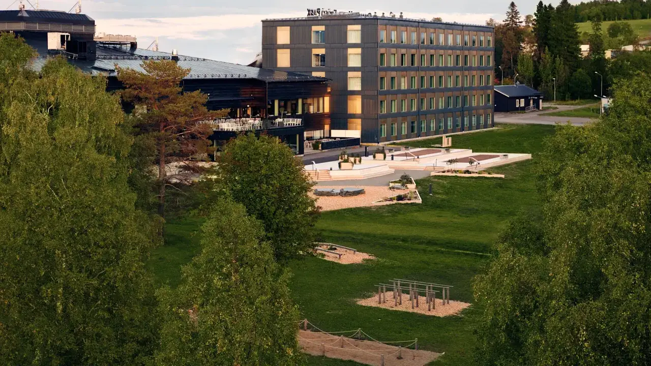 Moderna byggnader vid ett hotell park med gr&ouml;nskande tr&auml;d och utomhusgym.