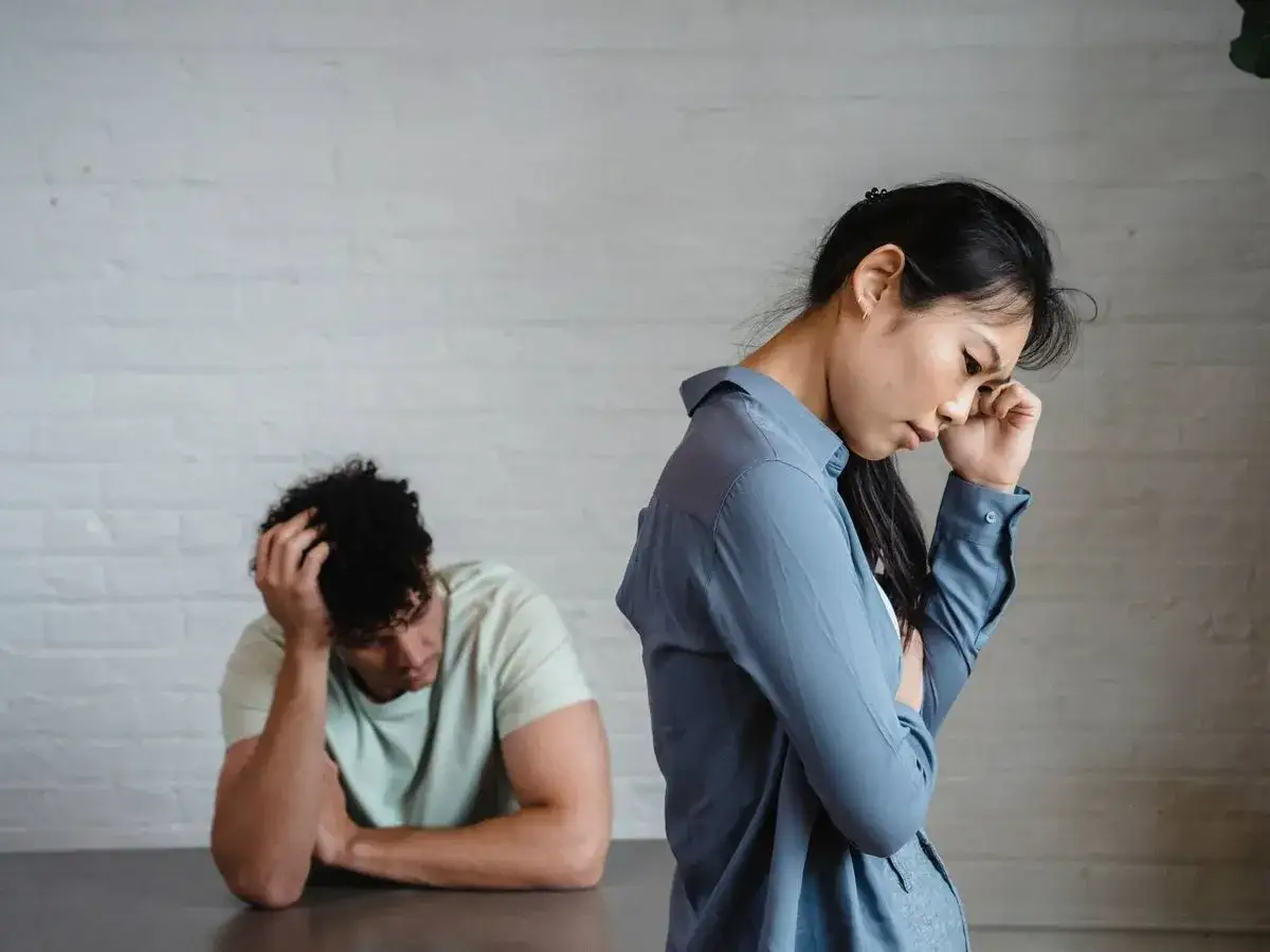 Pareja en silencio, ella con gesto de frustraci&oacute;n, &eacute;l con la mano en la cabeza, reflejando una **personalidad pasivo agresiva** en la tensi&oacute;n.