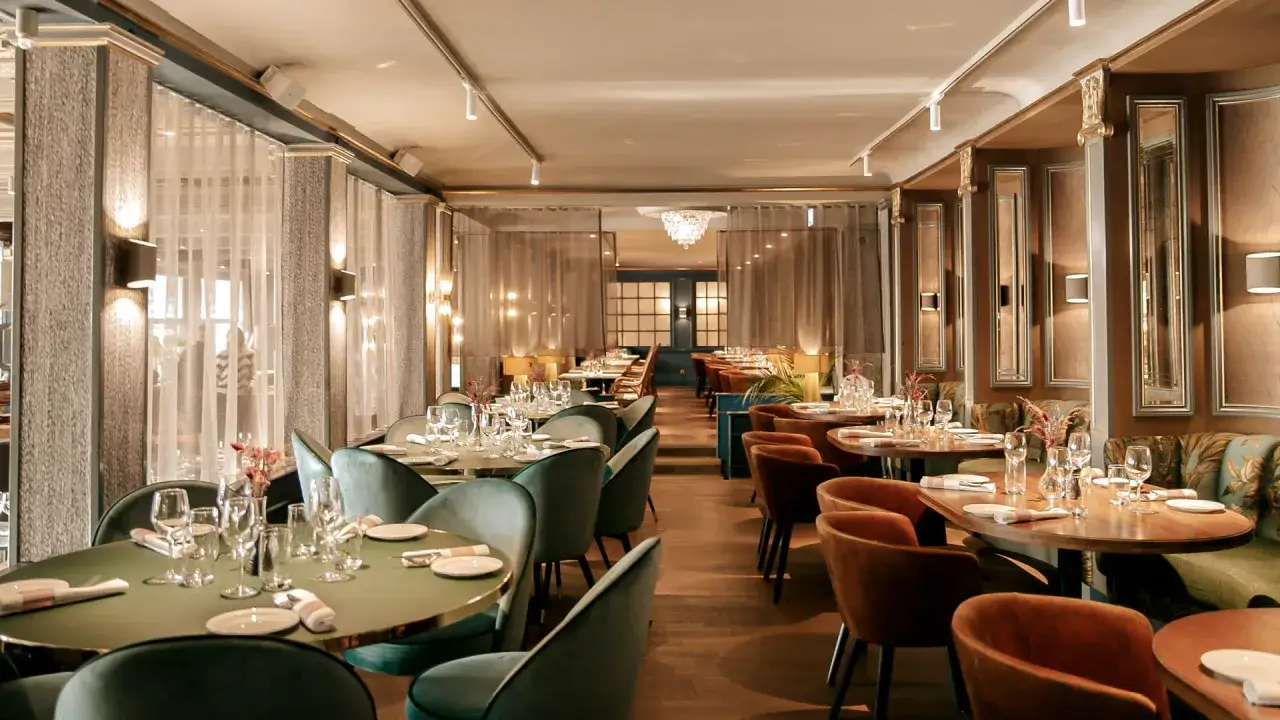Elegant dining room at Hasselbacken restaurang, Stockholm. Tables set with glassware and cutlery, plush seating, and soft lighting create a luxurious atmosphere.
