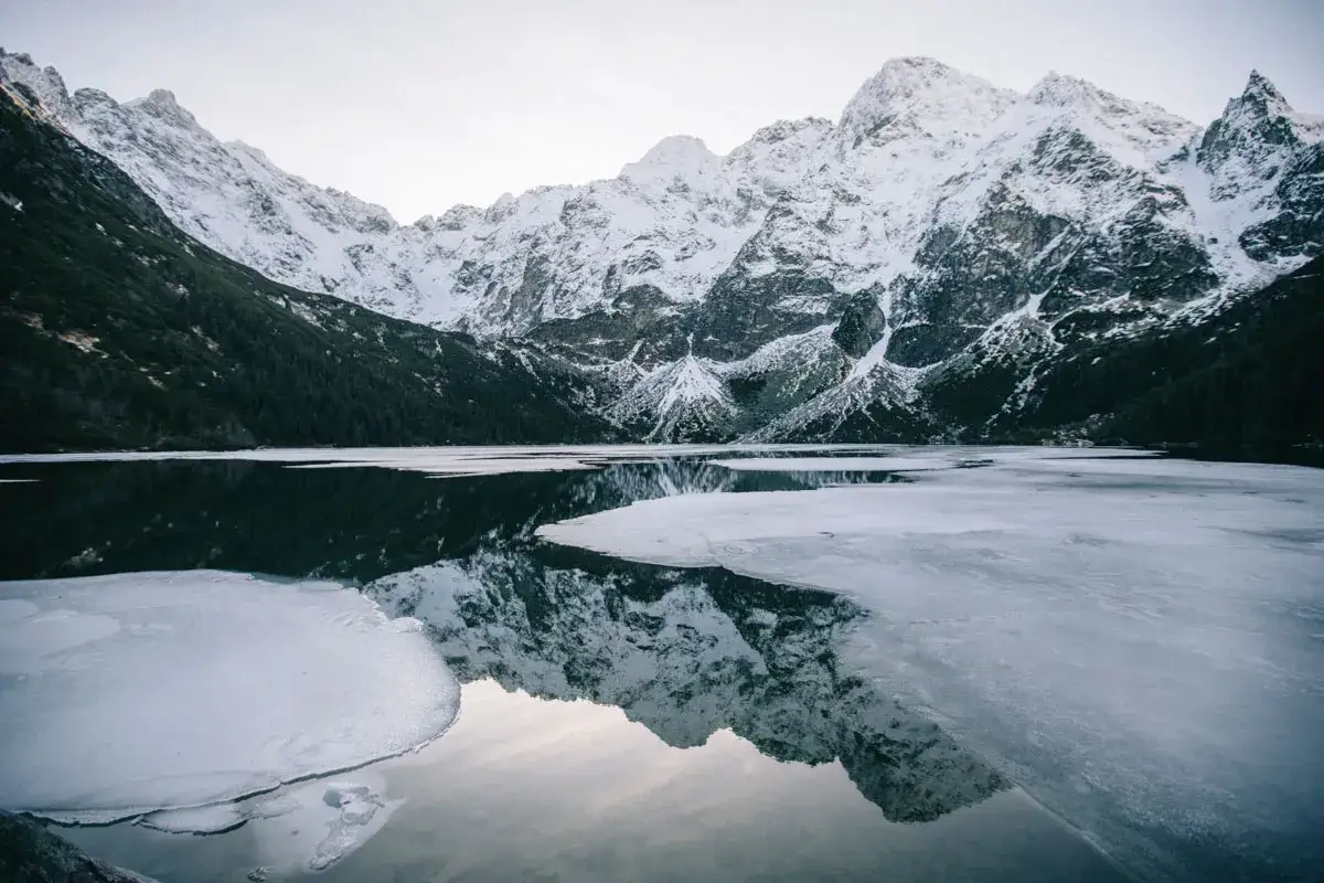 Lac gelé et montagnes enneigées dans les Tatras en Pologne, reflétant la beauté hivernale.