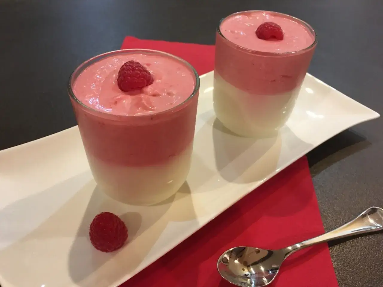 Deux verrines de mousse chocolat blanc et framboise, garnies d'une framboise fra&icirc;che.
