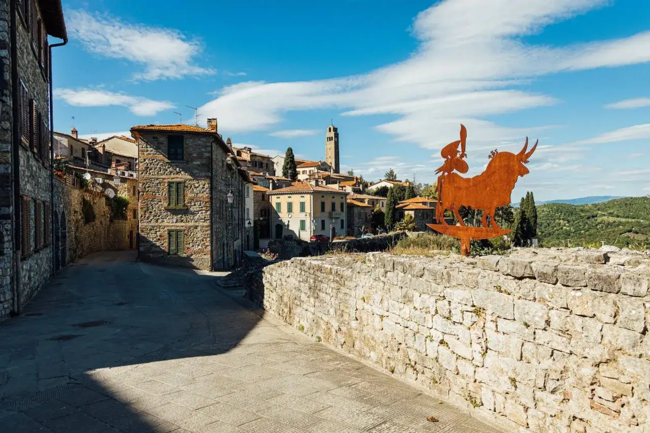 Un'antica strada di Civitella in Val di Chiana, con un'installazione artistica di un toro e un guerriero, invita a scoprire cosa vedere in questo borgo toscano.