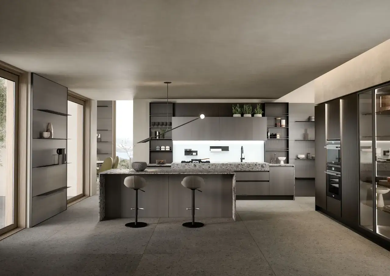 Cocina moderna y alargada con isla central, perfecta para distribuir el espacio. Muebles oscuros, encimera de cuarzo y taburetes.