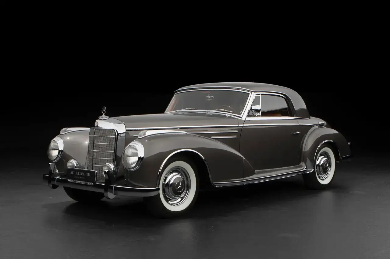 Elegancki, szary Mercedes 300 z lat 50. z chromowanymi detalami i białymi oponami, prezentowany na czarnym tle.