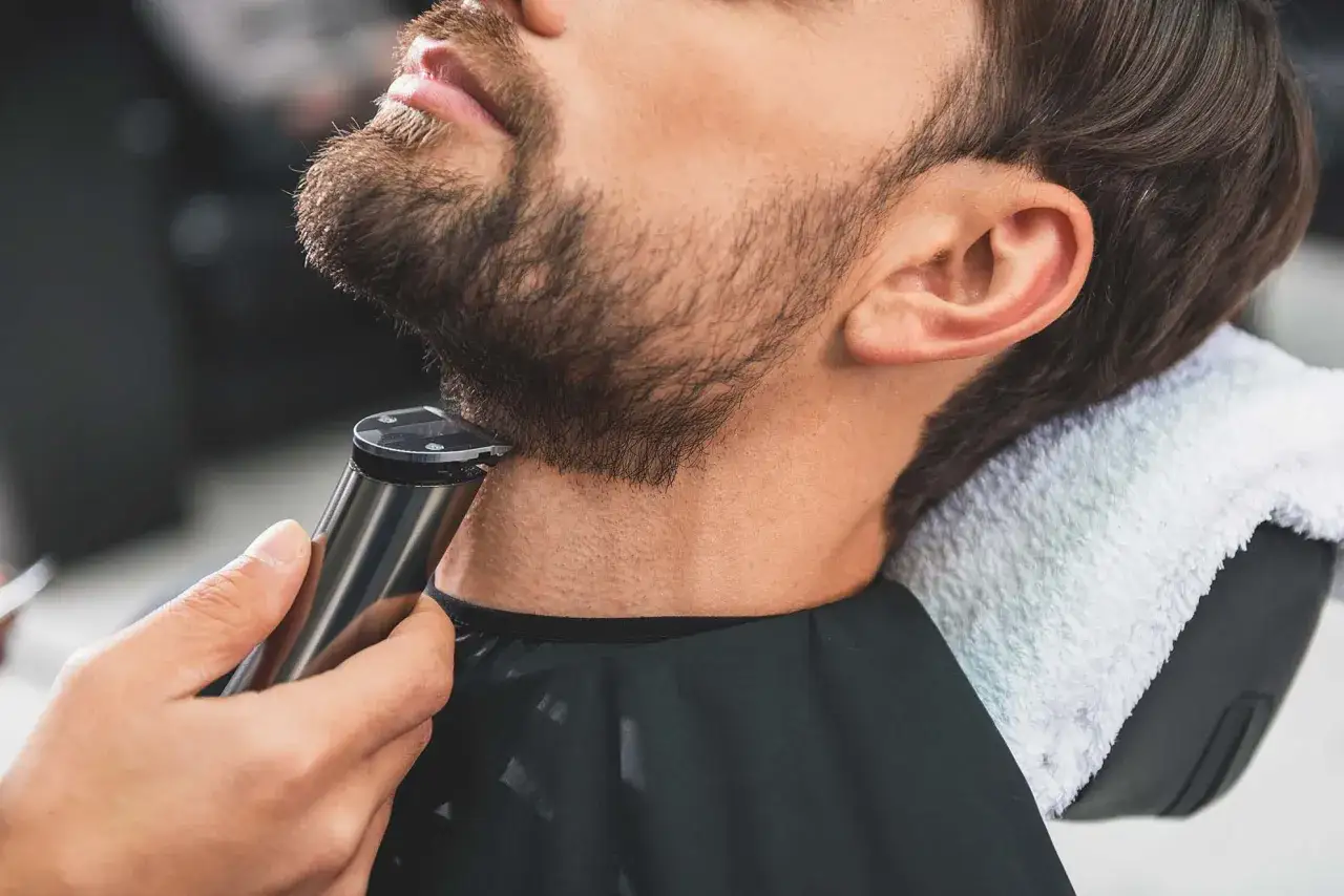 Barbero perfilando barba, ideal para encontrar los mejores tipos de barba para cara redonda y estilizar el rostro.