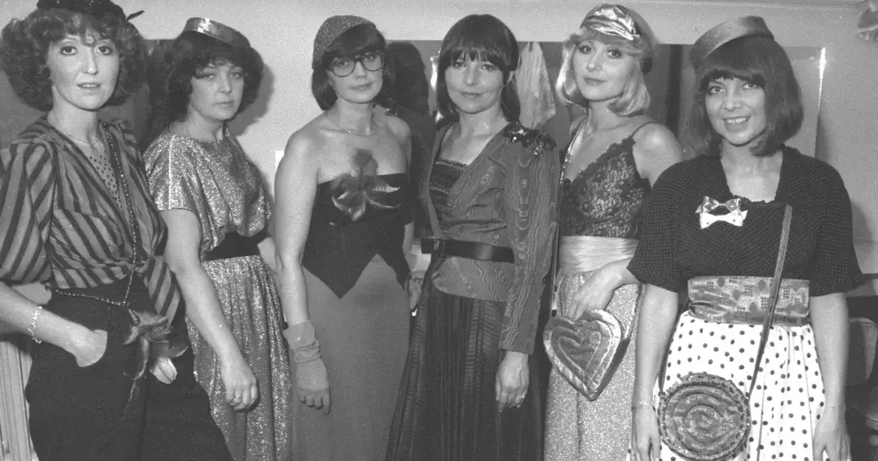 Sześć kobiet w stylizacjach z lat 80. prezentuje swoje stroje, być może przygotowując się do występu z alibabki utwory.