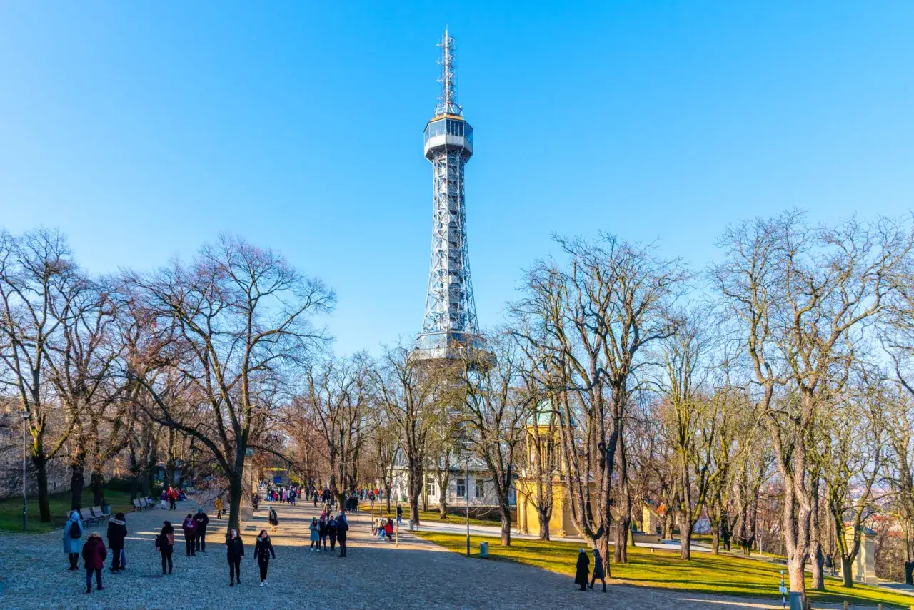 La tour P&eacute;trin se dresse fi&egrave;rement sous un ciel bleu, entour&eacute;e d'arbres d&eacute;nud&eacute;s et de visiteurs profitant d'une promenade hivernale.