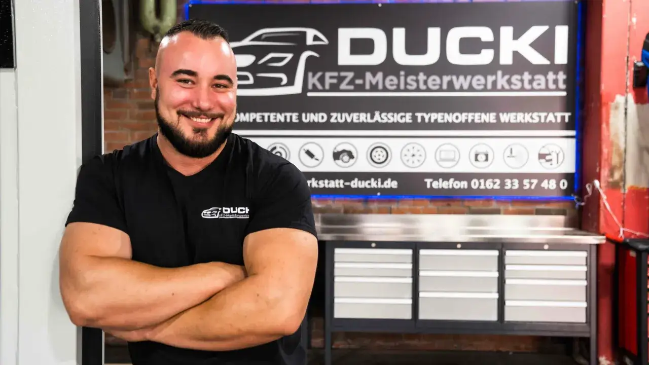 L&auml;chelnder Kfz-Meister vor seiner Werkstatt. Hier gibt es spannende Kfz Meister Stellenangebote f&uuml;r engagierte Schrauber.