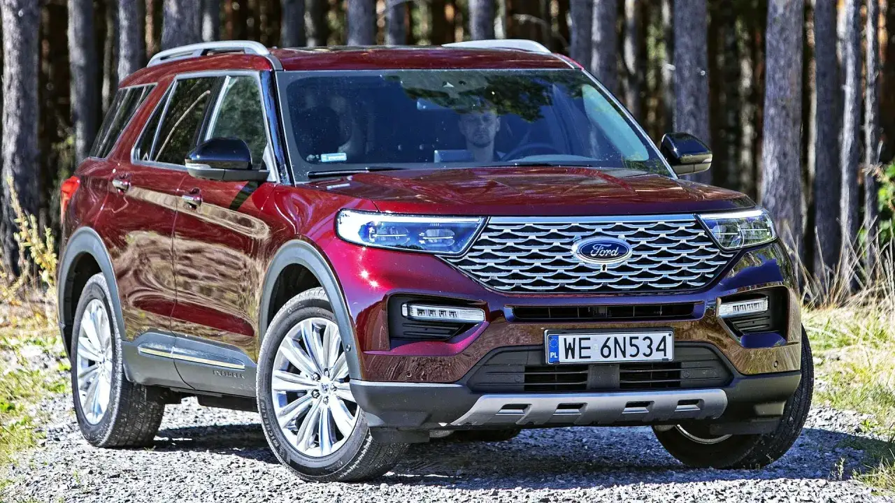 Czerwony Ford Explorer 4x4 zaparkowany na leśnej drodze.