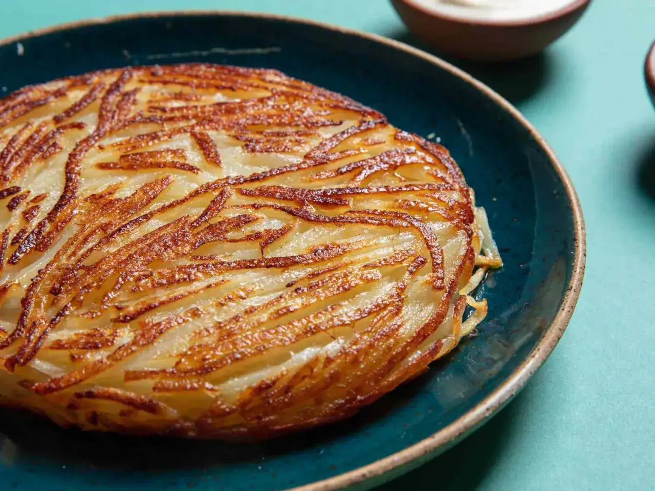 Krispig pommes anna p&aring; en bl&aring; tallrik, gyllene och perfekt tillagad.