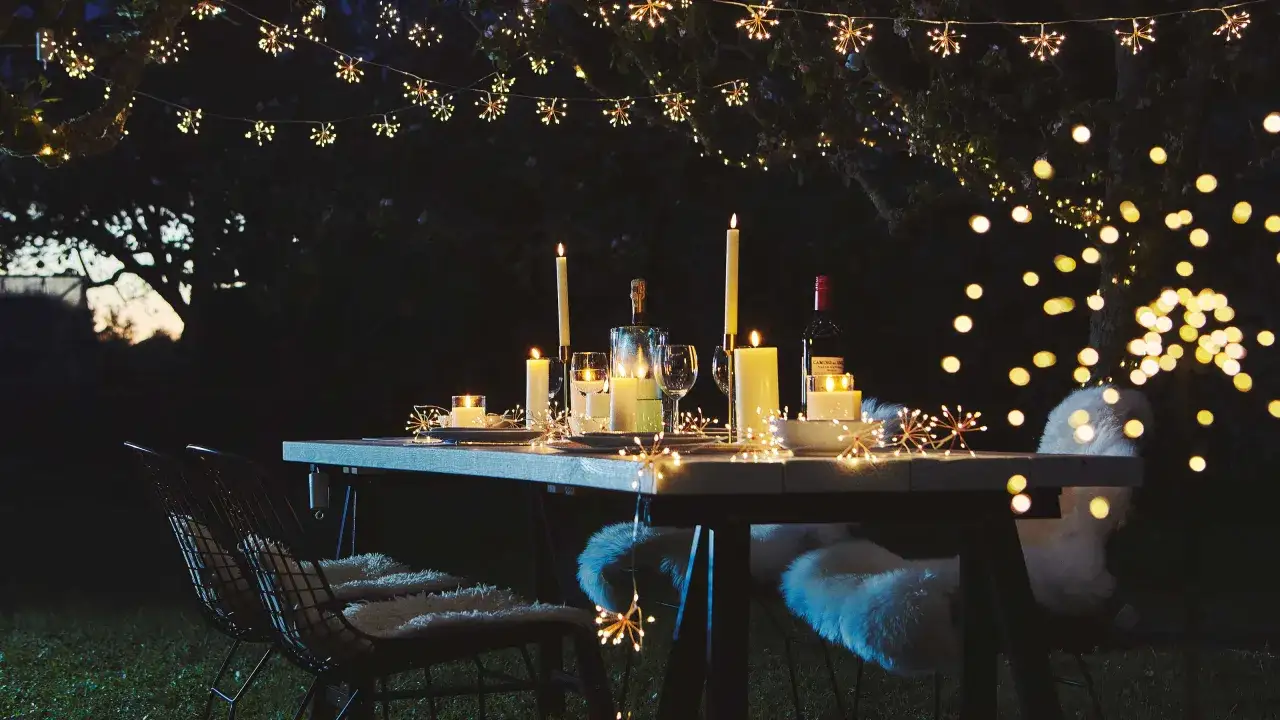 Romantische Lichterketten und Kerzen schaffen eine zauberhafte Atmosph&auml;re f&uuml;r kleine Partyideen im Freien.