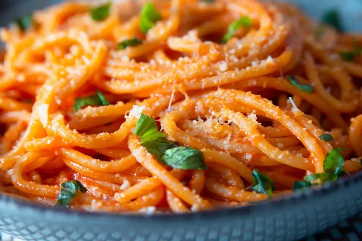 Spaghetti conditi con un cremoso sugo per pasta al pomodoro e basilico, spolverati di parmigiano.