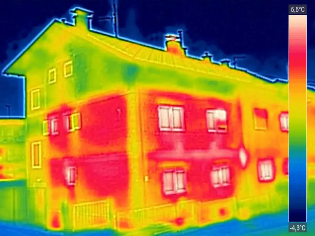 Analisi termica di un edificio con termocamera per edilizia. Zone rosse indicano dispersioni di calore, verdi e blu zone più fredde.