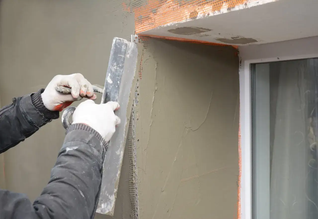 Lavori di intonacatura attorno alle finestre, con un cappotto che protegge le spallette. Si nota lo spessore dello strato di intonaco.