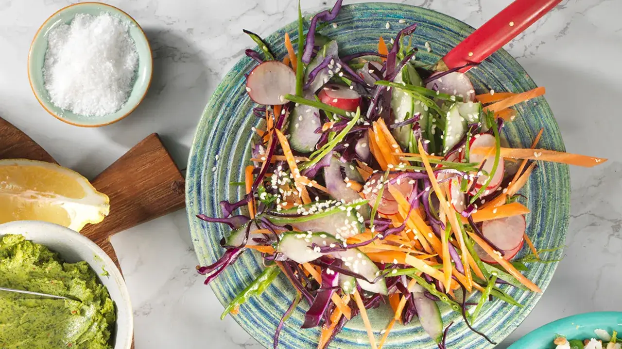 En f&auml;rgglad asiatisk k&aring;lsallad med mor&ouml;tter, r&auml;disor och gurka, toppad med sesamfr&ouml;n. Serveras med en gr&ouml;n dipp och citron.