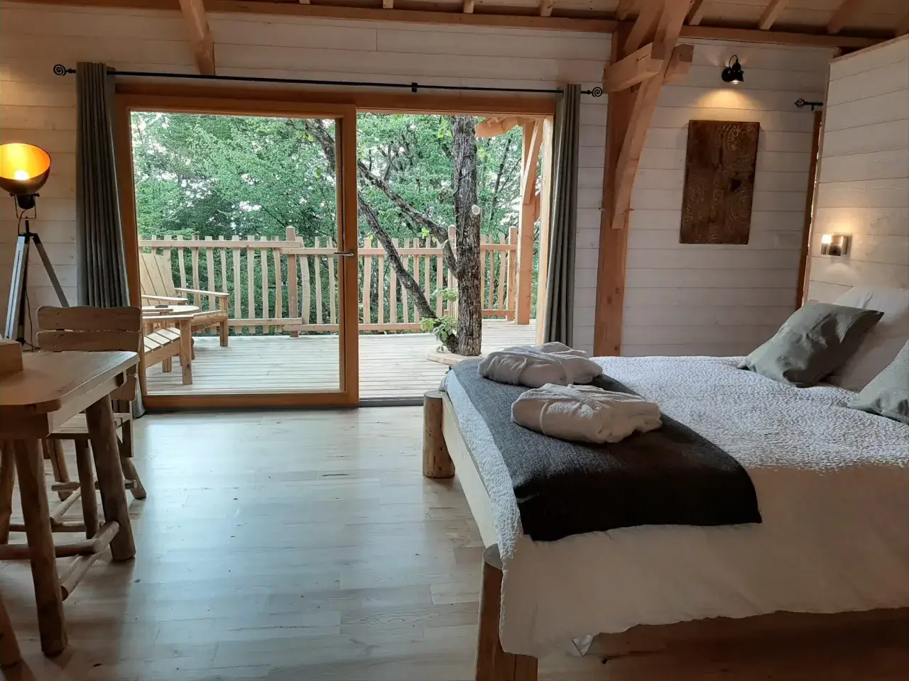 Chambre douillette dans une cabane dans le Jura, avec un grand lit, une terrasse et vue sur la for&ecirc;t.