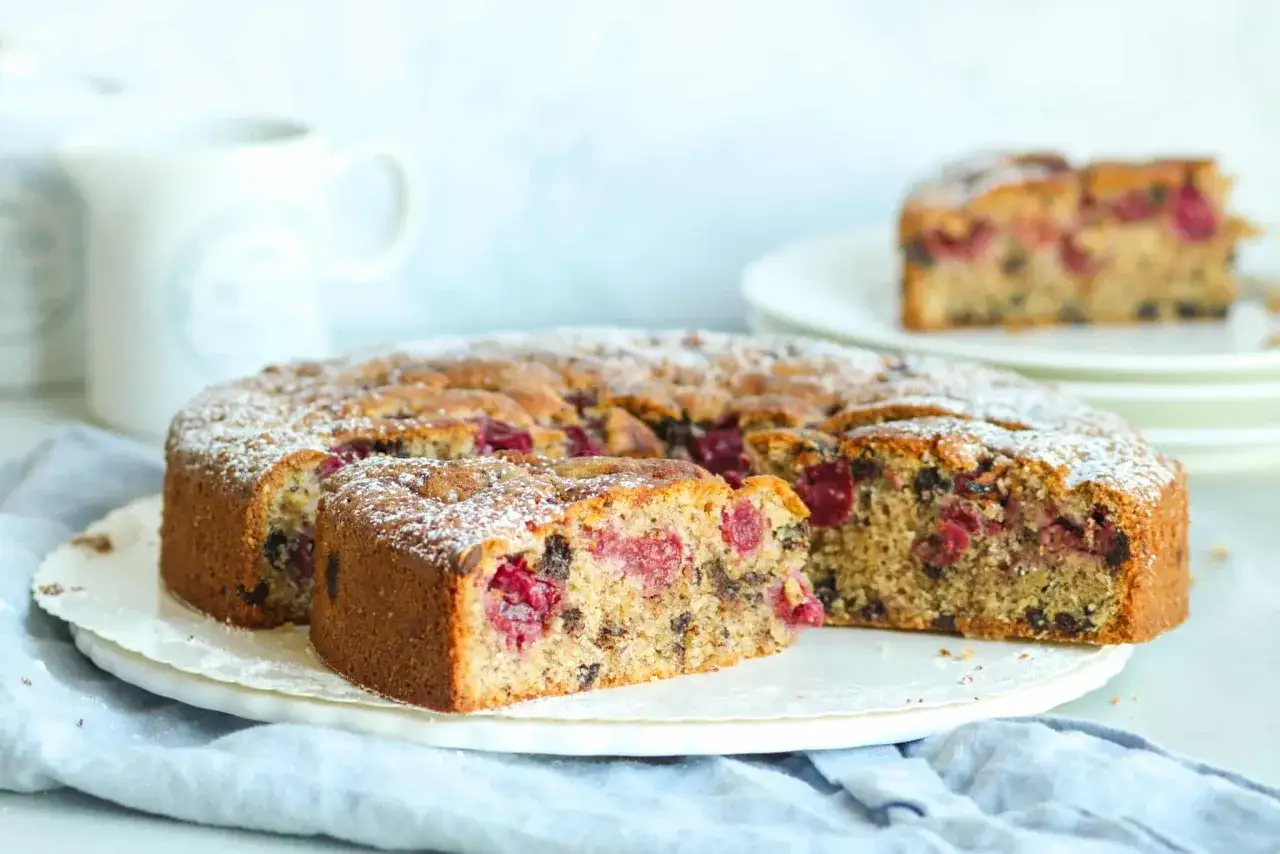 Saftiger Kirschkuchen mit Schokostückchen, bestäubt mit Puderzucker. Ein köstliches Kirschkuchen Rezept für jeden Anlass.