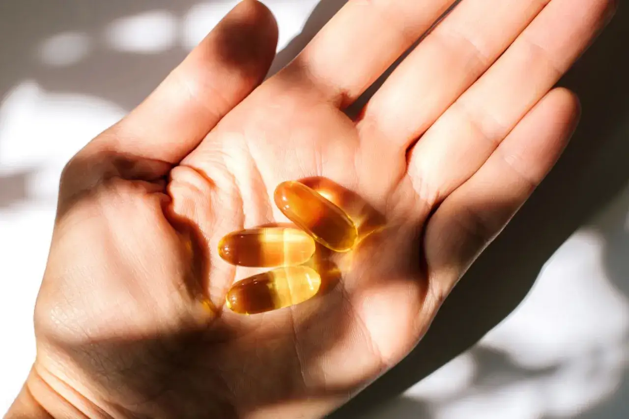 Trzy kapsułki omega 3 w dłoni. Kiedy brać omega 3? Najlepiej po posiłku, by zapewnić lepsze wchłanianie.